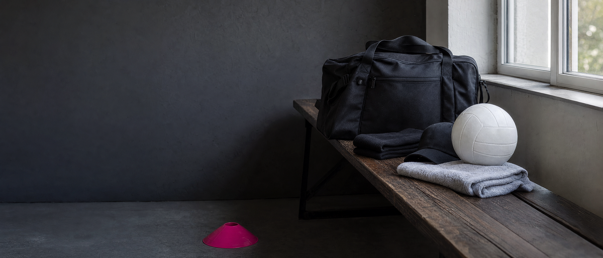 Neutrale schwarze Sporttasche und Trainingszubehör auf einer Umkleidebank.